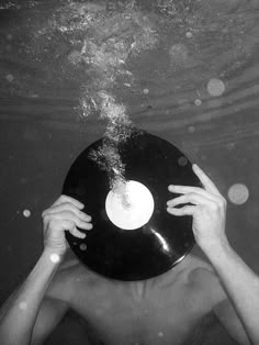 a man under water holding up a record in front of his face to the camera