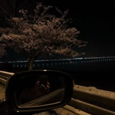 a person taking a photo with their cell phone in the rear view mirror at night