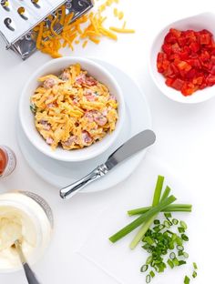 a white table topped with bowls filled with pasta and veggies next to utensils