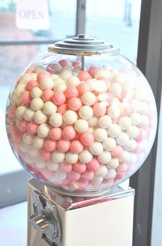 a gummy machine filled with lots of pink and white balls