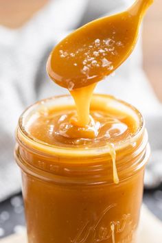 a spoon full of caramel sauce on top of a jar