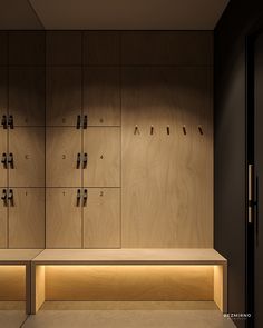 an empty bench in the middle of a room with wooden lockers on both sides