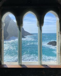 an arched window overlooking the ocean and rocks