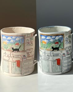 two mugs with designs on them sitting next to each other