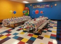 a party hall with tables and balloons on the wall, decorated for a child's birthday