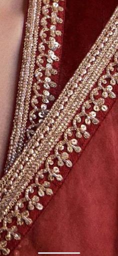 the back of a woman's red dress with gold beading