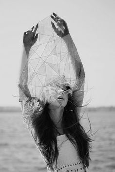 a woman with her hair in the wind holding up a piece of paper over her head