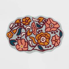 an embroidered patch with flowers and leaves on the side, sitting on top of a white surface