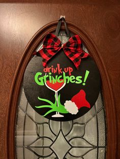 the grinch door hanger is decorated with red and black ribbon, which says drink up grinches