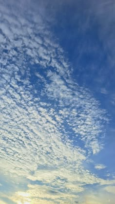 an airplane flying in the sky with clouds and sun going down on it's horizon