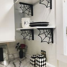 black and white spider webs on the wall above shelves in a kitchen with marble counter tops