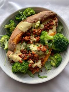 a white plate topped with broccoli and meat covered in sauce on top of it