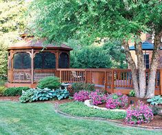 a wooden gazebo sitting next to a lush green park filled with flowers and trees