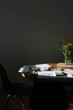 a vase with yellow flowers sitting on top of a table next to a black chair