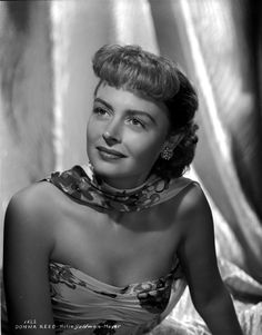 an old black and white photo of a woman in a dress with a scarf around her neck