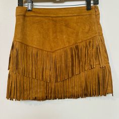 Add A Touch Of Western Style To Your Wardrobe With This Fort Worth Camal Fringe Skirt. The Skirt Features A Solid Pattern And Is Made Of A Combination Of Polyester And Spandex, With A Suede Fabric Type. It Has A Mid-Rise And A Zip Closure For Ease Of Wear. The Skirt Is Perfect For Travel, Parties, Or Casual Occasions, And Comes In A Size Xs. It Also Includes Built-In Shorts For Added Comfort. The Brown Color And Fringe Accents Give The Skirt A Unique Look That Is Sure To Make A Statement. Whethe Fringe Skirt, Suede Fabric, Solid Pattern, Western Style, Fort Worth, Western Fashion, Brown Color, Womens Bottoms, Fort