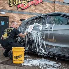 a man is washing his car with water