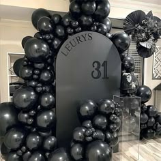 black balloons are arranged in front of a sign for luxury's 81th birthday