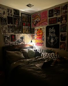 a bedroom with posters on the wall and a bed in front of it is lit by a lamp