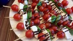 a white plate topped with skewered tomatoes and mozzarella on toothpicks