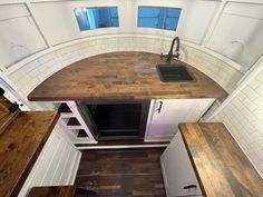 an overhead view of a kitchen with wooden counter tops and white cabinets in a tiny home