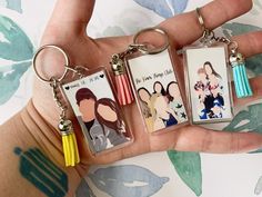 three keychains with pictures of people on them in the palm of someone's hand