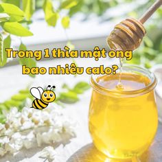 a jar filled with honey sitting on top of a table next to flowers and leaves