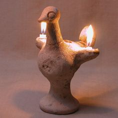 a duck shaped candle holder with two lit candles