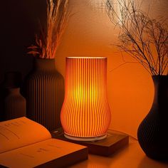 a lamp that is on top of a table next to some vases and an open book