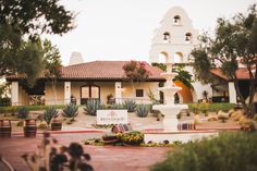 a large white building with a fountain in front of it and lots of greenery