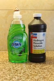 two bottles of dish soap and a bottle of mouthwash on a counter