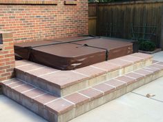 a brown suitcase sitting on top of steps next to a brick wall and wooden fence