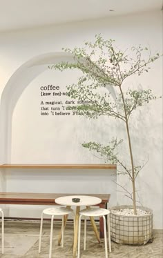 two tables and a bench in front of a wall with writing on it that says coffee