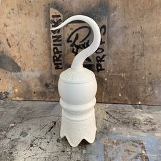 an odd looking white vase sitting on top of a wooden floor next to a wall