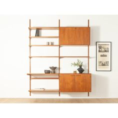 a wooden shelf with shelves and vases on it next to a wall mounted painting