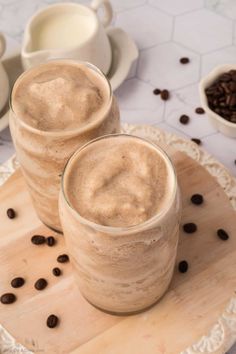 two glasses of coffee sitting on top of a wooden tray