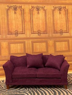 a purple couch sitting on top of a zebra print rug in front of a wooden wall