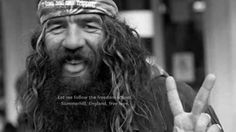 a man with long hair wearing a bandana and making the peace sign in front of him