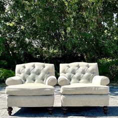 two white couches sitting next to each other on top of a stone floor covered ground