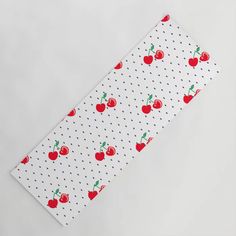 a white table cloth with red apples and polka dots on the side, along with a green leaf