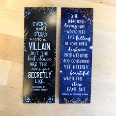 two bookmarks with words on them sitting on top of a wooden table next to each other