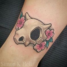 a skull with pink flowers on it's side is shown in this tattoo design