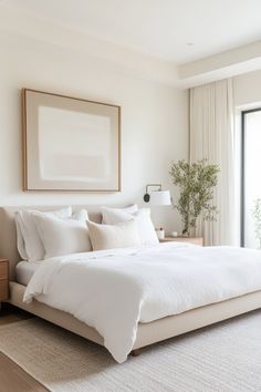 a large white bed sitting in a bedroom next to a tall wooden framed art piece