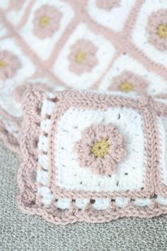 a crocheted blanket with pink and white flowers on it sitting on the floor