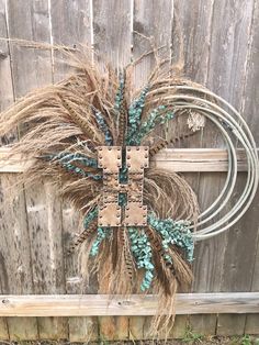 a wreath made out of dried grass sitting on top of a wooden fence