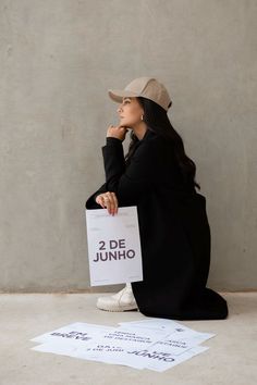 a woman sitting on the ground holding a sign that says 2 dejunho in spanish