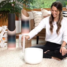 a woman is sitting on the floor playing with her remote control and other items in front of her