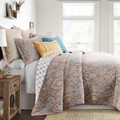 a bed in a bedroom with white walls and wooden flooring next to a window