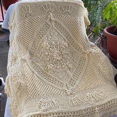 a crocheted blanket sitting on top of a table next to a potted plant