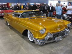 antique cars are on display at an auto show, with people standing around looking at them